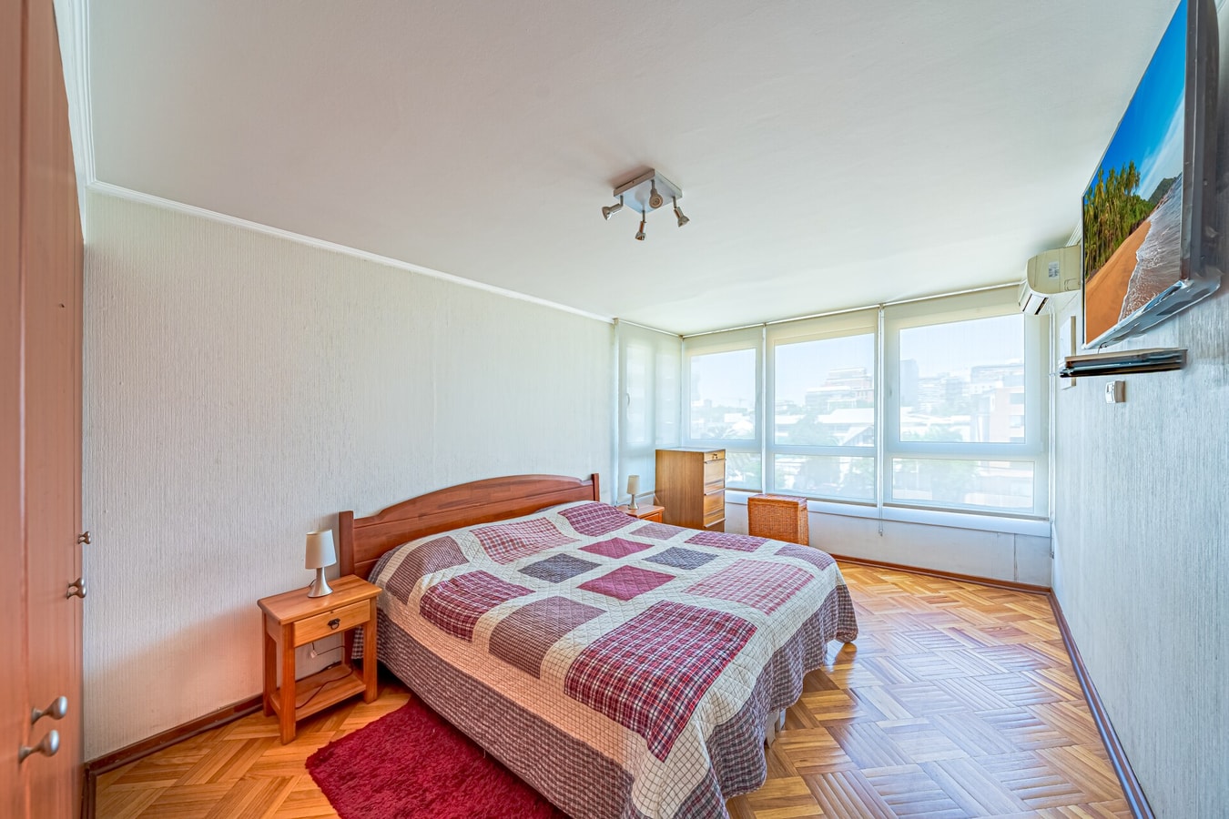 Dormitorio principal con cama matrimonial, mesas de noche a ambos lados y televisor en la pared.