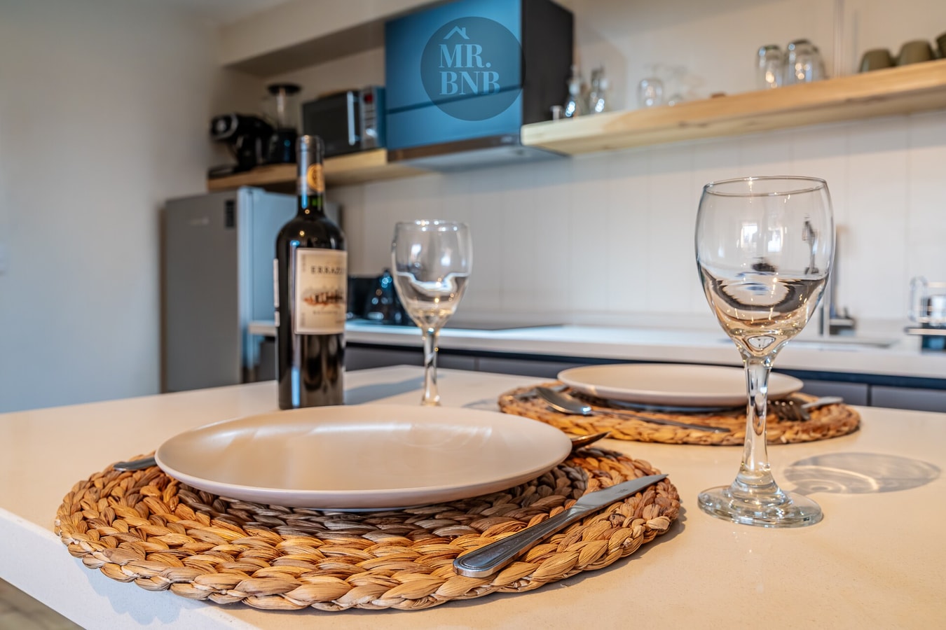 Detalle de la barra puesta con plato, copas de vino y botella, sobre individual de fibra natural