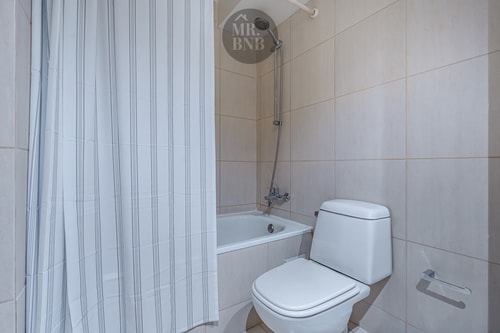 Baño con tina, cortina de baño e inodoro