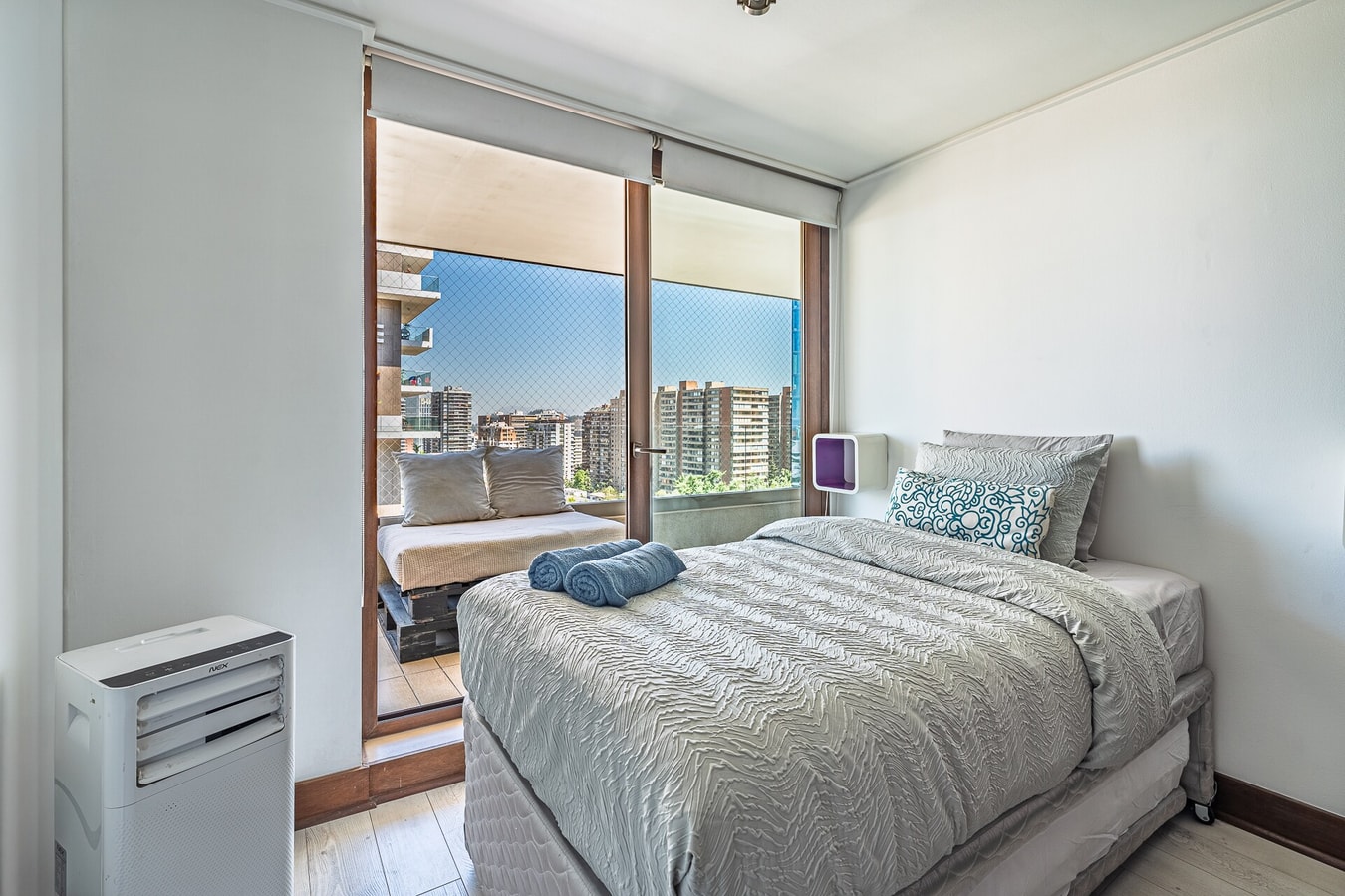 Dormitorio con cama, ventanal amplio y calefactor portátil