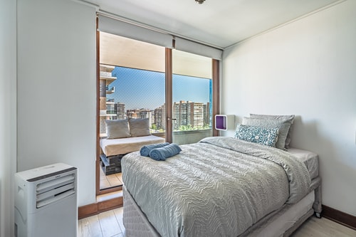 Dormitorio con cama, ventanal amplio y calefactor portátil
