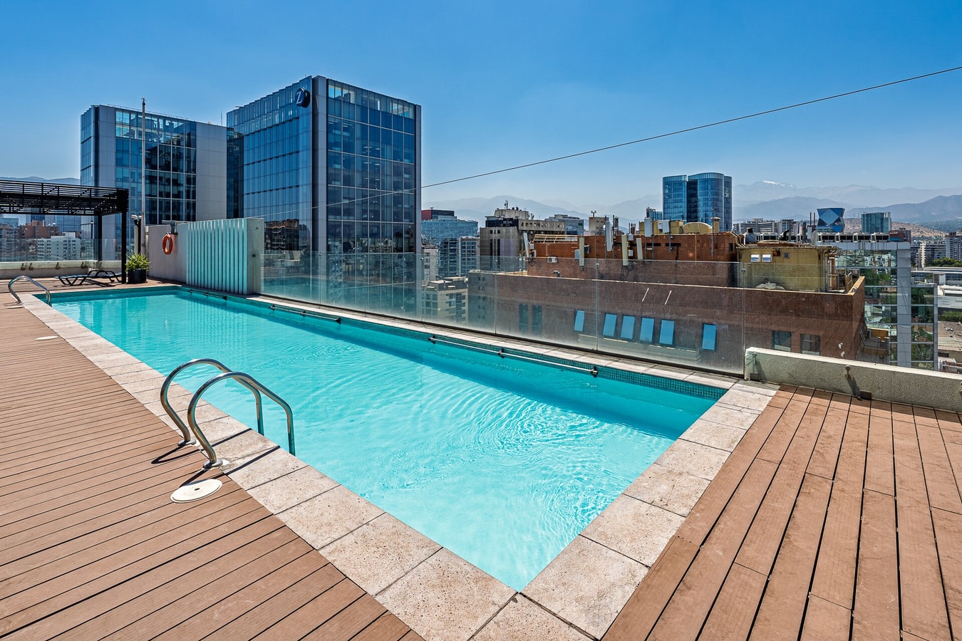 Piscina en azotea del edificio, con deck de madera y vista a la ciudad