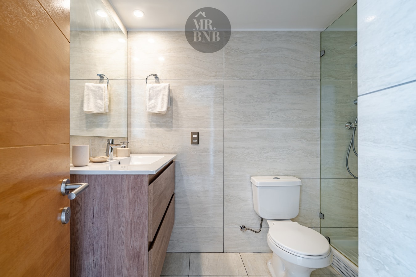 Baño con mueble de madera, lavamanos y espejo