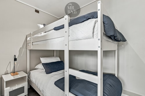 Dormitorio con litera de dos camas, velador y ropa de cama azul