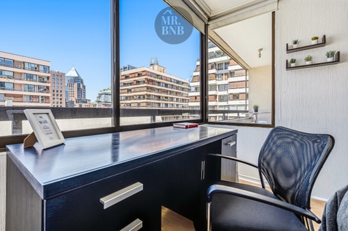 Escritorio de madera oscura con silla junto a ventanal, zona de trabajo dentro del dormitorio