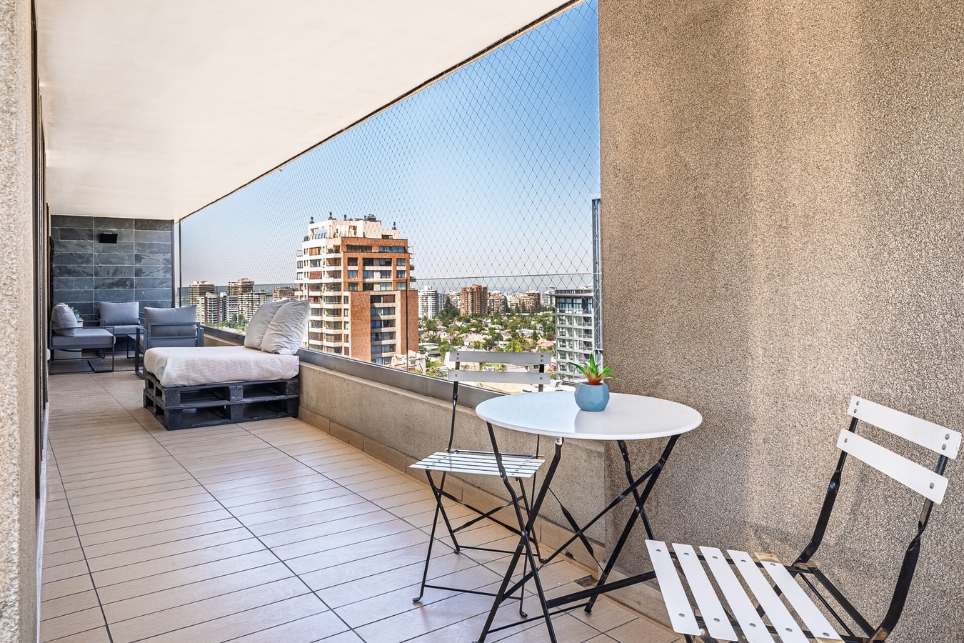 Terraza privada con mesa y sillas plegables, vista a edificios de la ciudad