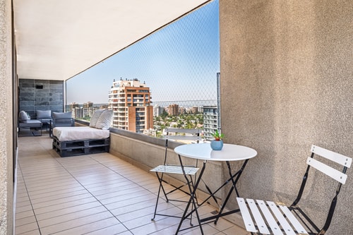 Terraza privada con mesa y sillas plegables, vista a edificios de la ciudad