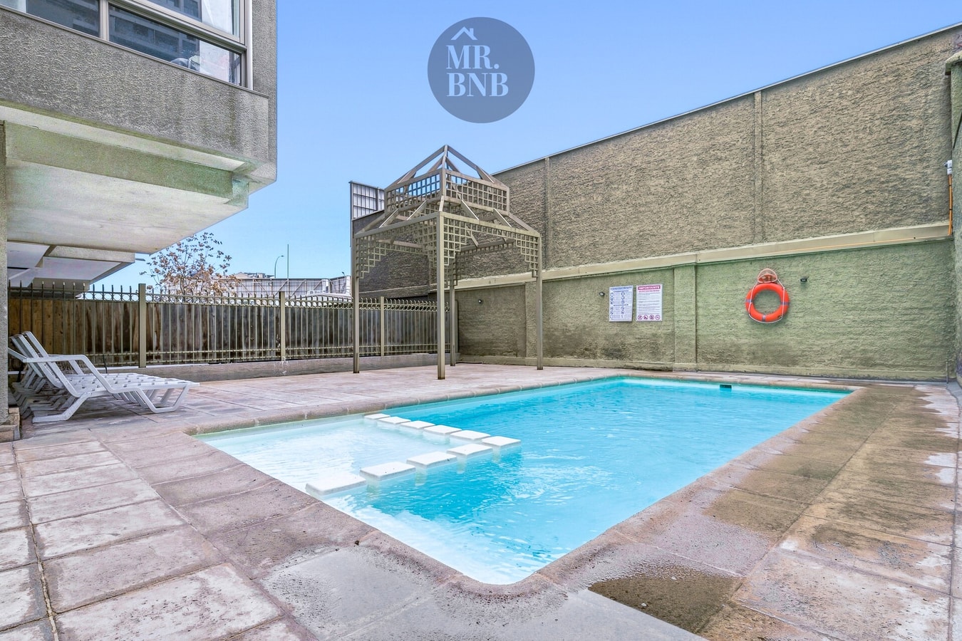 Piscina exterior del edificio con reposeras y cerco perimetral