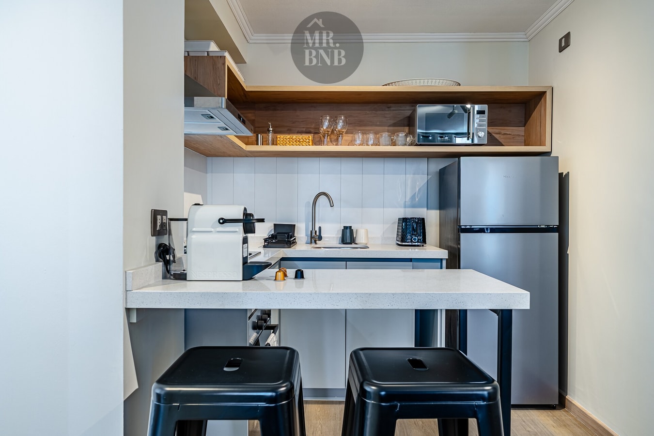 Cocina con barra, dos banquetas negras y refrigerador