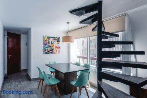 Comedor con mesa y sillas verdes, escalera caracol negra y cuadro decorativo en la pared