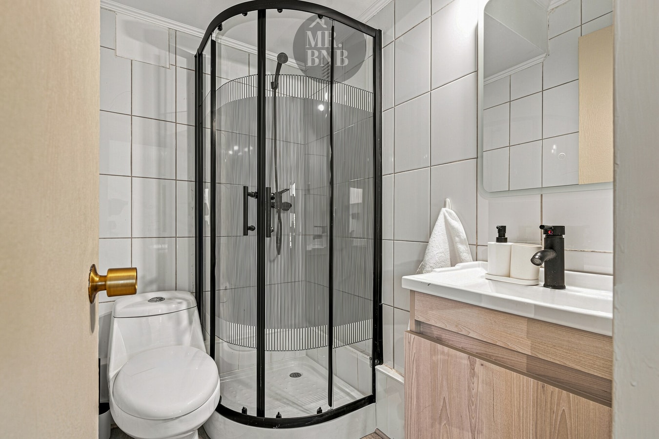 Baño con ducha semicircular de vidrio y vanitorio con detalles dorados.
