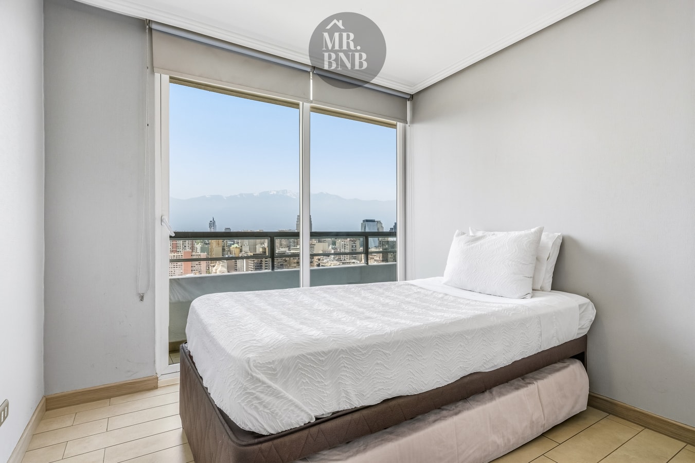 Dormitorio con cama, radiador eléctrico y ventanal con vista a la cordillera