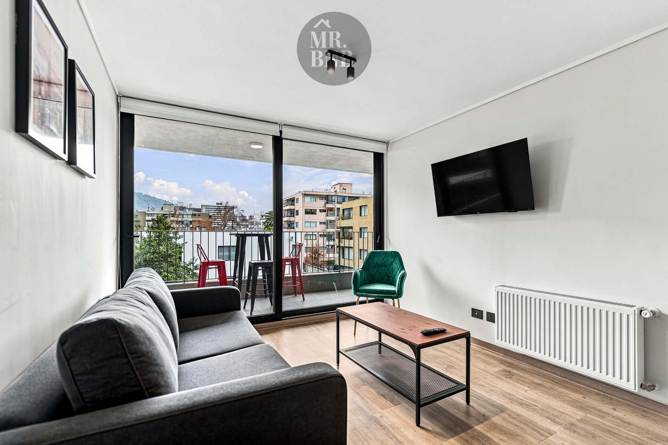 Living con sofá gris, mesa de centro, TV montada en la pared y radiador junto a la ventana