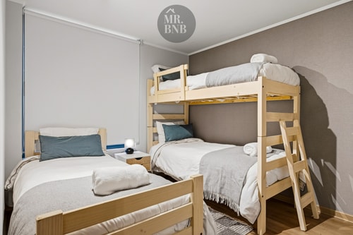 Dormitorio con cama de dos plazas y litera adosada en madera clara