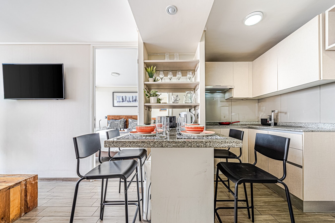 Cocina con isla, taburetes negros y repisas abiertas