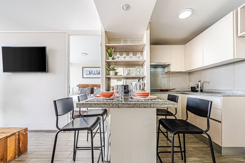 Cocina con isla, taburetes negros y repisas abiertas