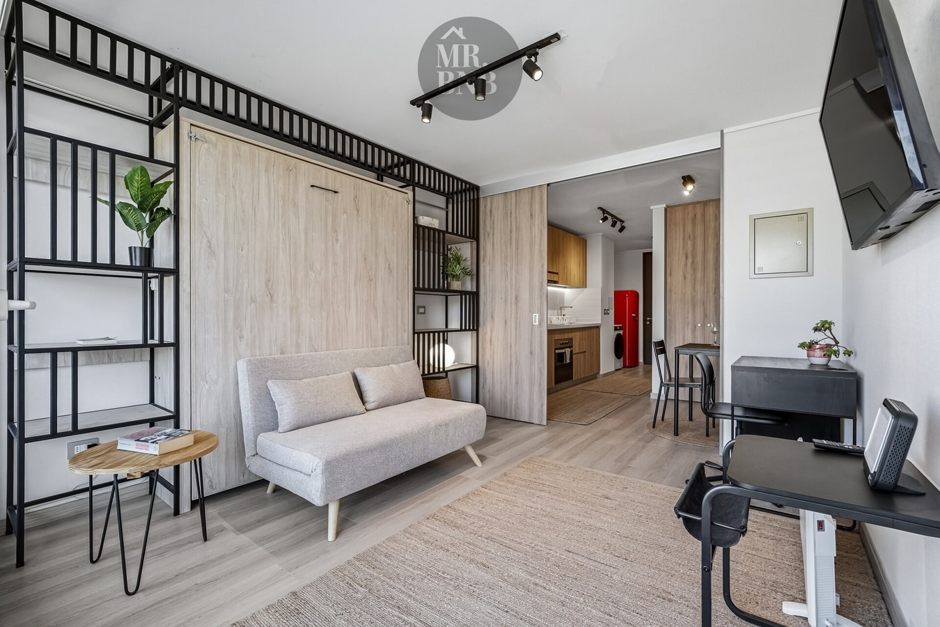 Estudio con cama Murphy retráctil, estantería metálica, sofá y cocina integrada