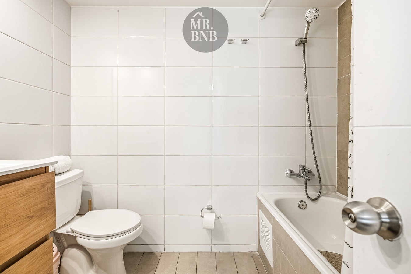 Baño con tina, ducha y grifería, azulejos blancos