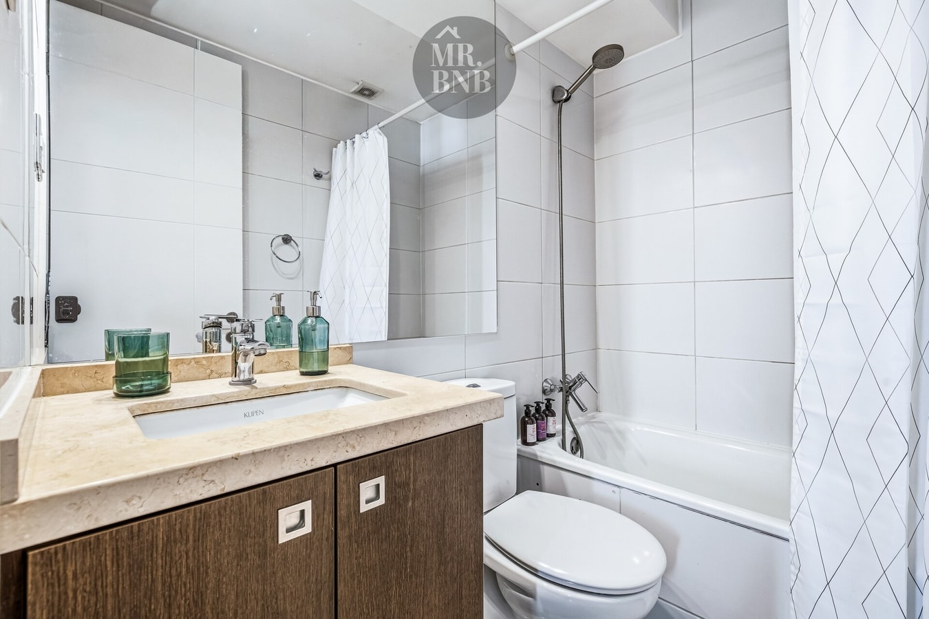 Baño con tina, cortina, mueble vanitorio de madera e inodoro