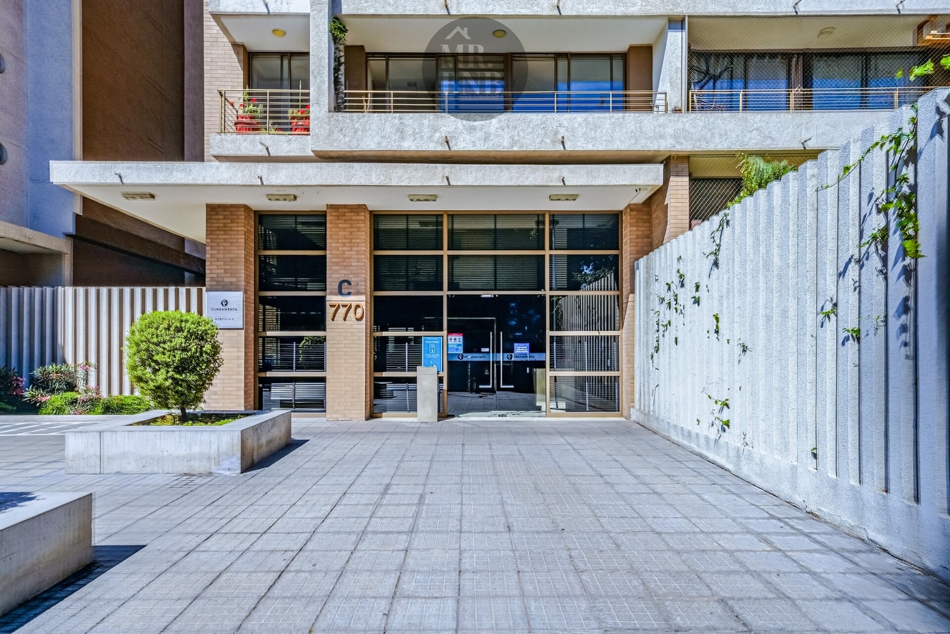 Fachada del edificio con acceso peatonal y jardinera exterior