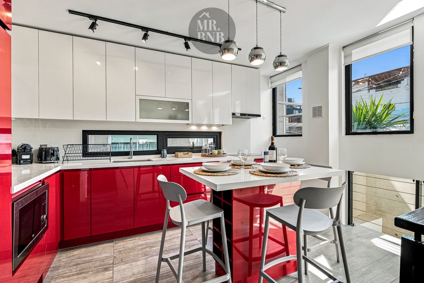 Cocina roja y blanca con isla central y taburetes, barra de desayuno