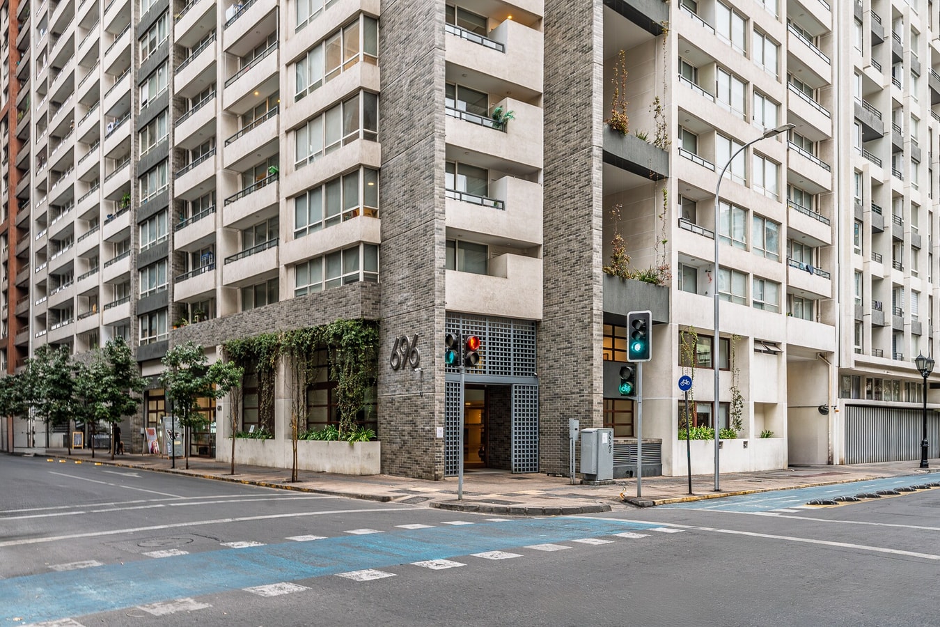 Fachada del edificio en esquina, con acceso peatonal y semáforos en la calle.