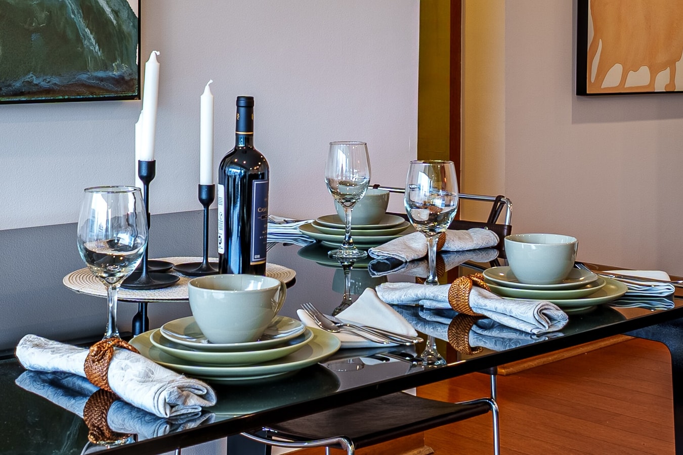Mesa de comedor puesta con vajilla, copas y candelabros.