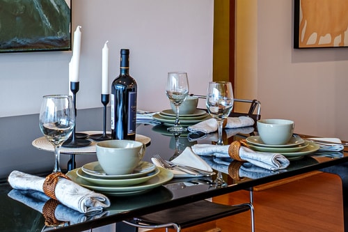 Mesa de comedor puesta con vajilla, copas y candelabros.