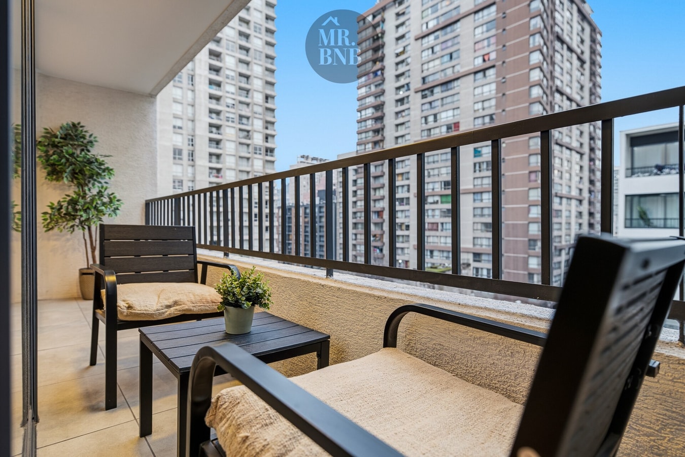 Terraza privada con sillones, mesa baja y vista a edificios de altura