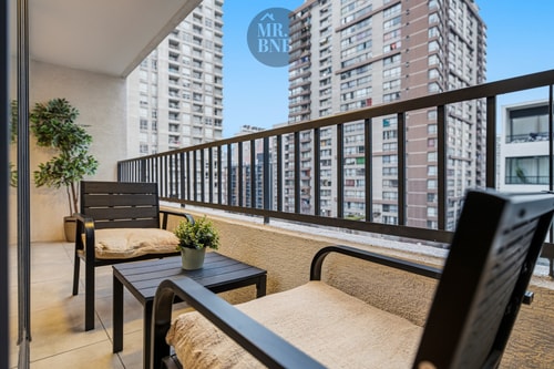 Terraza privada con sillones, mesa baja y vista a edificios de altura