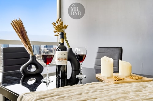 Dormitorio ambientado con botella y copas de vino, velas y vista a la ciudad de fondo