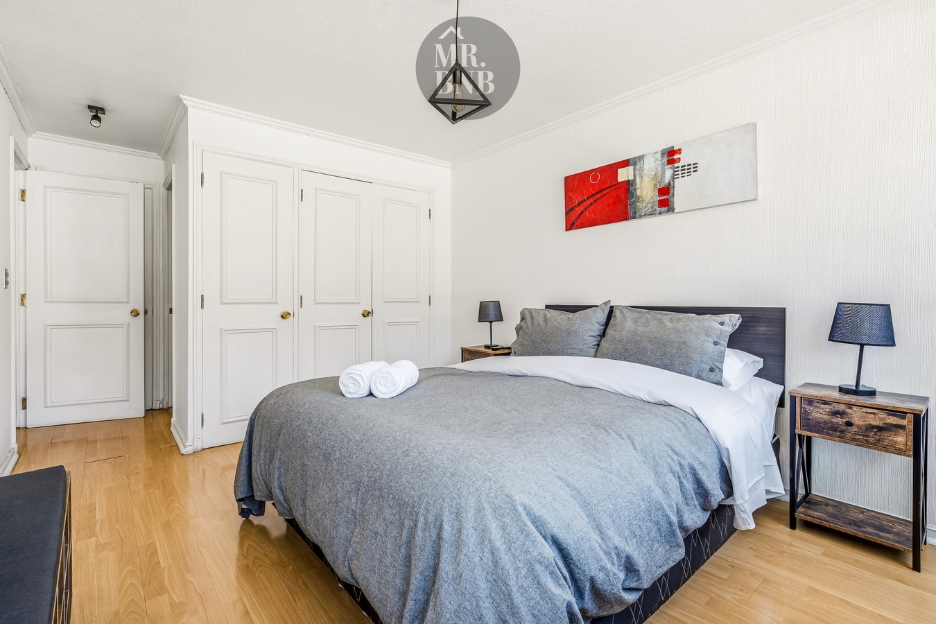 Dormitorio con cama matrimonial, closet blanco de varias puertas y cuadro decorativo en la pared