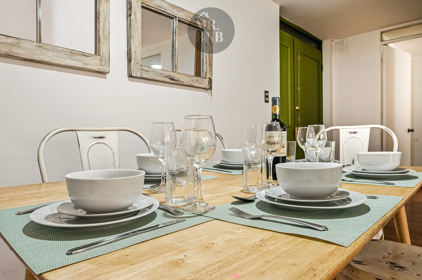 Mesa de comedor puesta con vajilla, copas y botella de vino