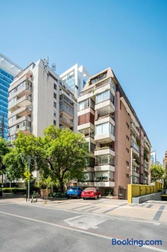 Fachada del edificio desde la calle, con veredas arboladas y autos estacionados