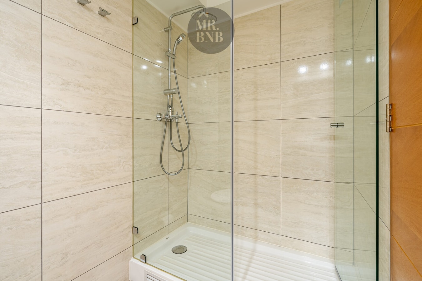 Ducha con puerta de vidrio y muro de cerámica clara