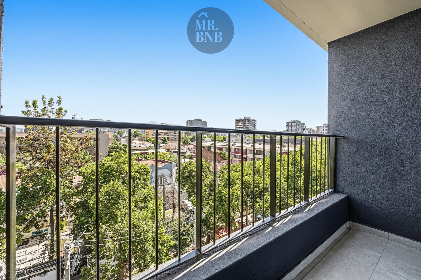 Balcón con baranda y vista hacia árboles y edificios del sector