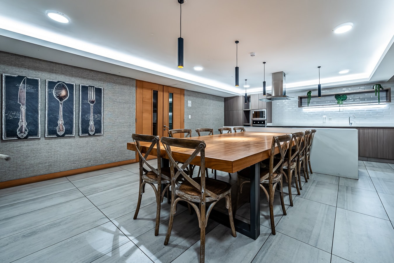 Salón común del edificio con mesa de comedor larga para varios comensales y sillas de madera