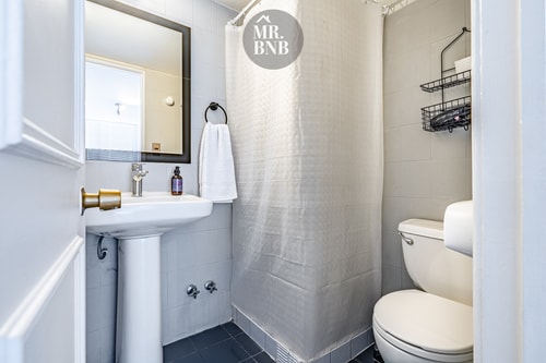 Baño con lavamanos, ducha con cortina y toallero