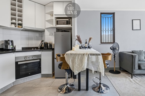 Cocina y comedor con mesa redonda, sillas altas y ventilador