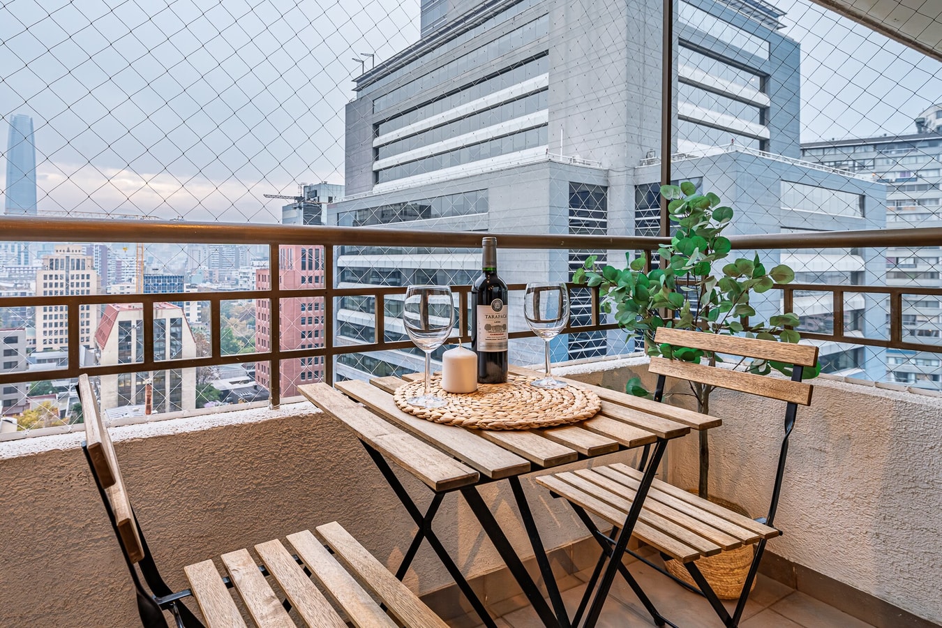 Balcón con mesa y sillas de madera, vista a edificios de la ciudad
