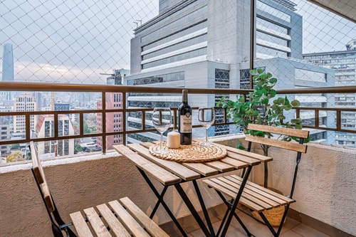 Balcón con mesa y sillas de madera, vista a edificios de la ciudad