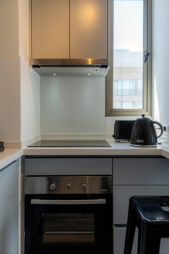 Cocina con encimera eléctrica, horno, campana y ventana