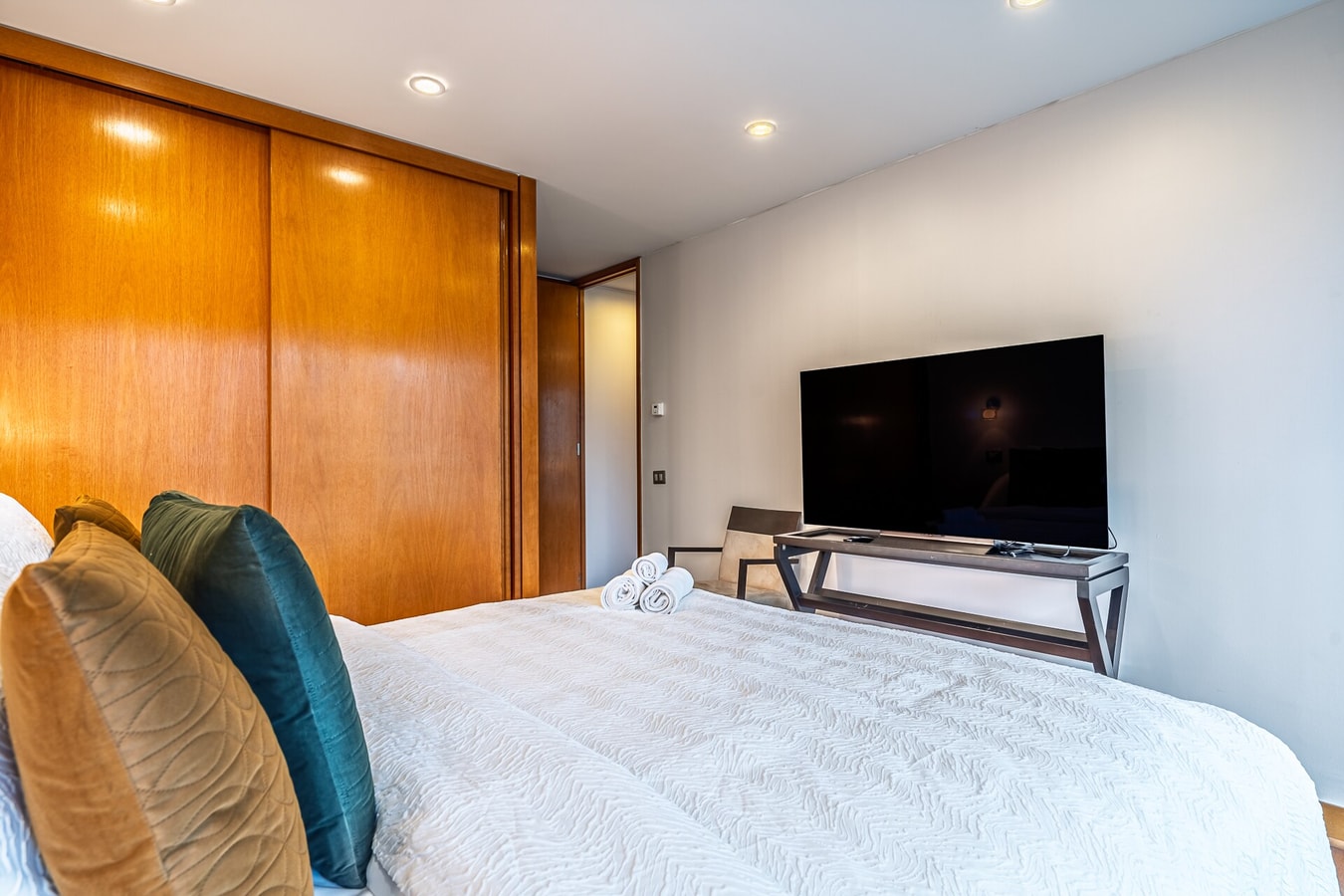Dormitorio con cama, veladores y televisor sobre mueble bajo.
