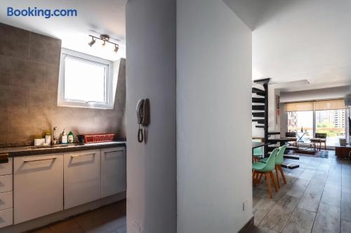 Cocina con mesón, muebles blancos con guardas de mosaico e intercomunicador en la pared