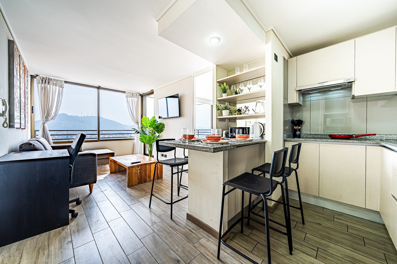 Living cocina integrada con barra, taburetes y vista a la ciudad
