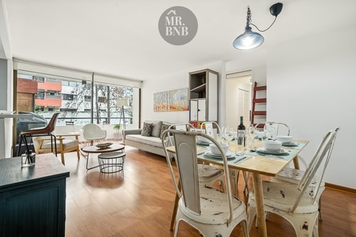 Living comedor con ventanal, mesa larga y sillas de distintos estilos