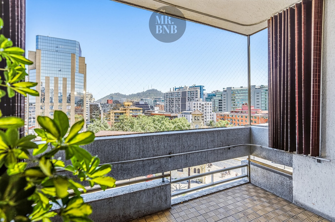 Balcón con vista panorámica a la ciudad y los cerros, cortinas y plantas