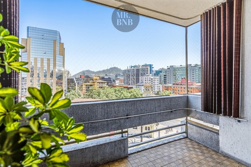Balcón con vista panorámica a la ciudad y los cerros, cortinas y plantas