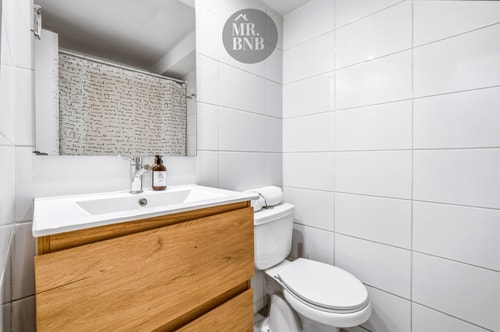 Baño con mueble vanitorio de madera, espejo e inodoro