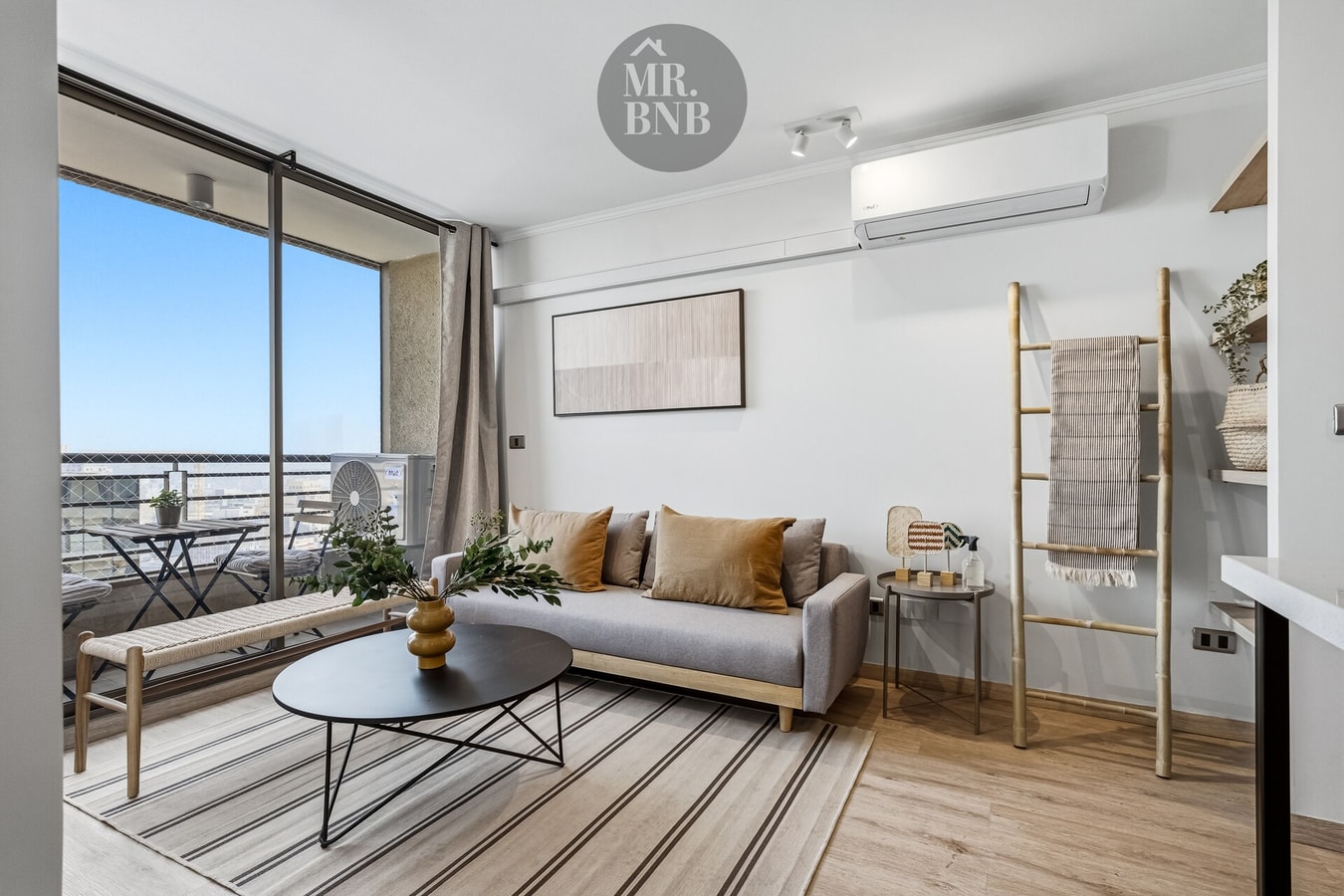 Living con sofá, equipo de aire acondicionado, alfombra y ventanal con vista a la ciudad
